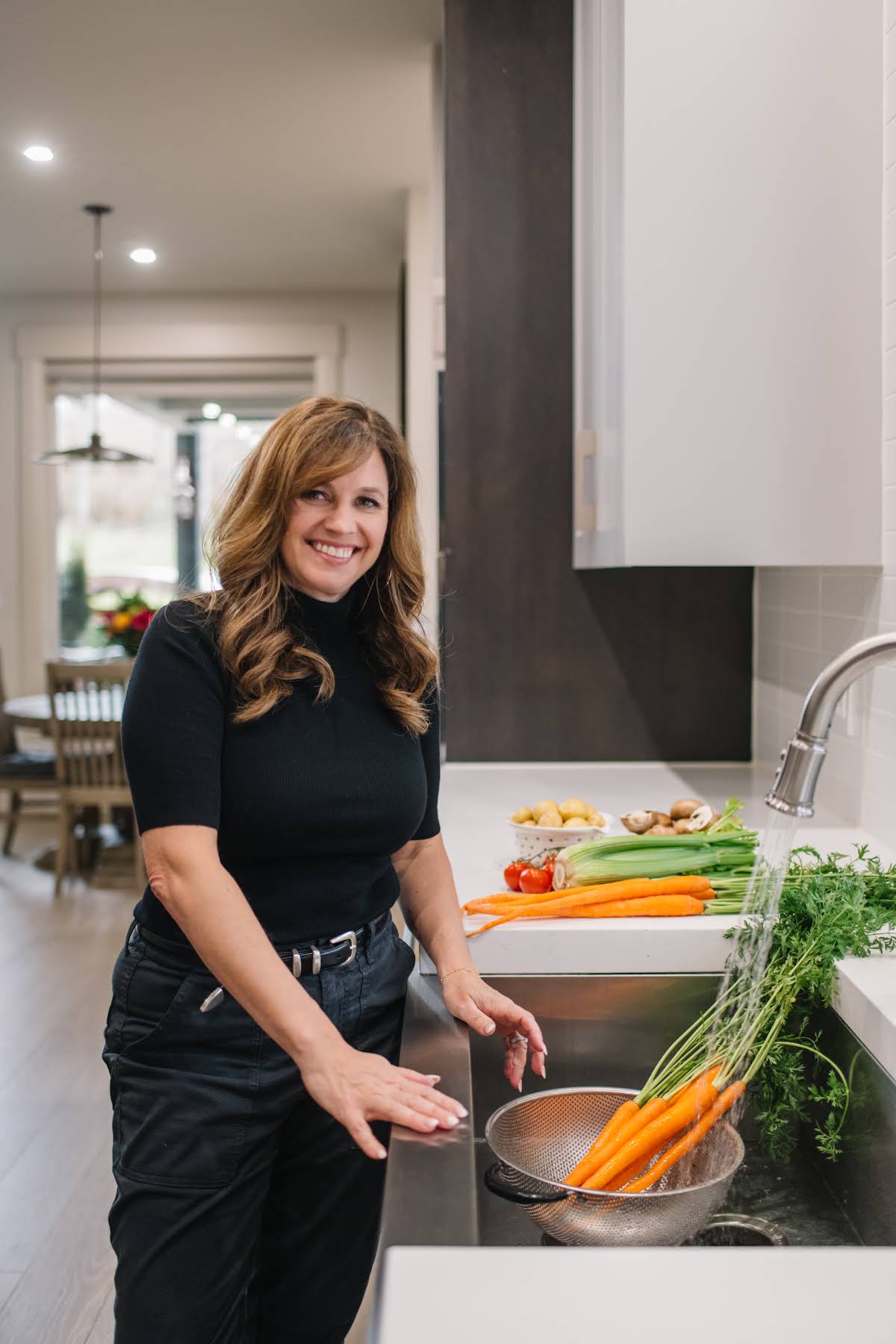 Holly Nilsson rinsing fresh carrots at her kitchen sink